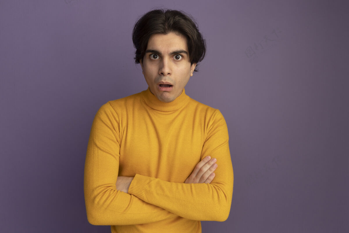 高领毛衣惊讶的年轻帅哥穿着黄色高领毛衣双手交叉隔离在紫色的墙上毛衣年轻手