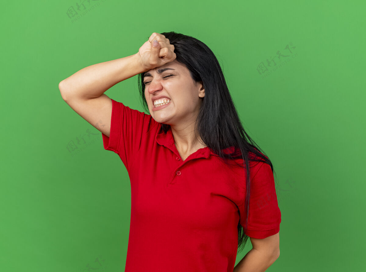 感觉疼痛的年轻患病妇女 手放在头上 眼睛闭着 头痛 隔离在绿色的墙壁上 留着复印空间眼睛痛苦脸