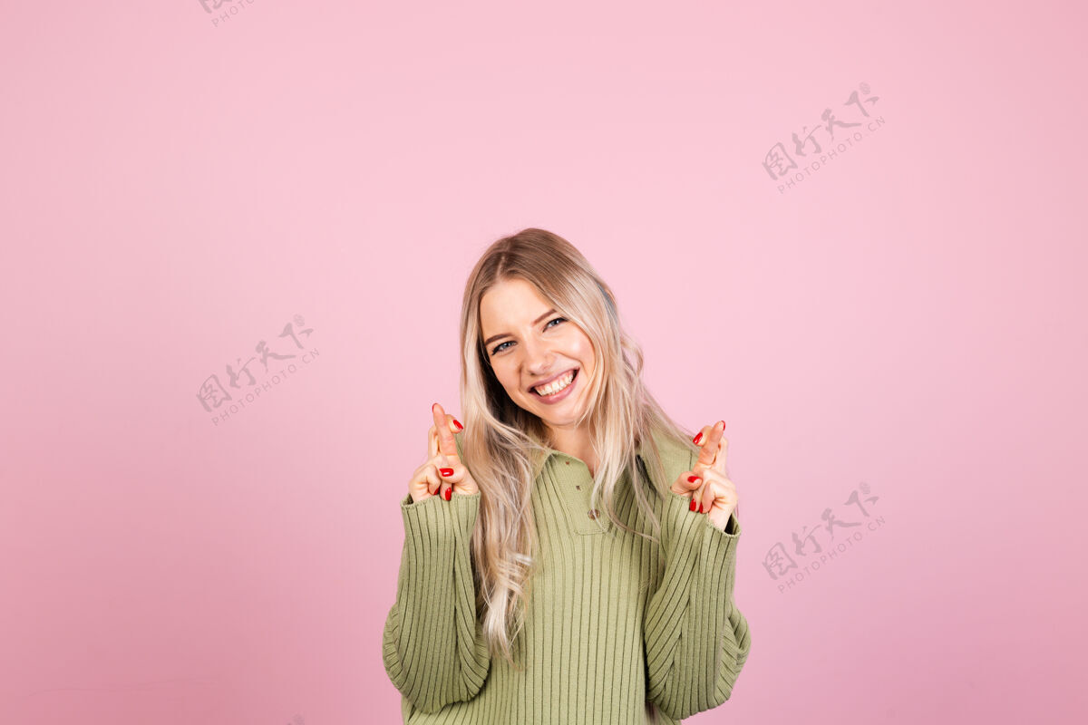 可爱粉色墙上穿着休闲毛衣的漂亮欧洲女人人嘴唇人