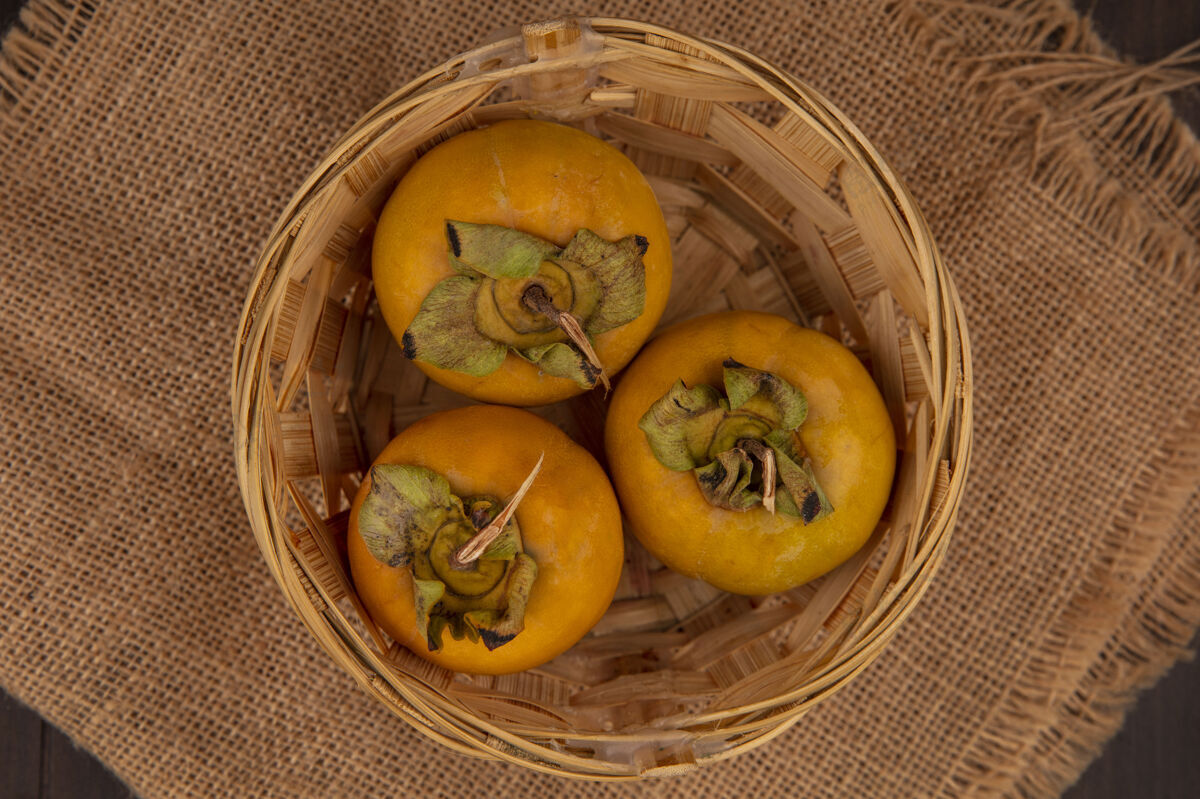 衣服木桌上的布袋上的桶上有机柿子水果的俯视图袋食品柿子