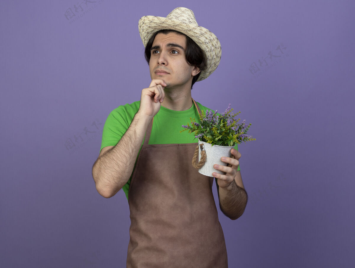 穿想着看着身边穿着制服的年轻男园丁戴着园艺帽捧着花盆里的花抓着下巴花花园人