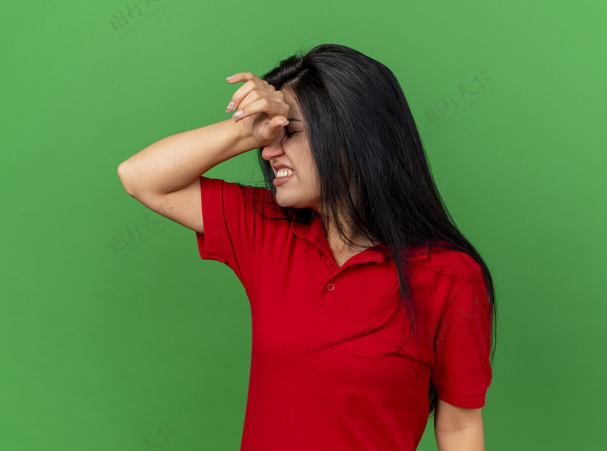 衣服疼痛的年轻病妇 手放在头上 眼睛闭着 头痛 被隔离在绿墙上人感觉人