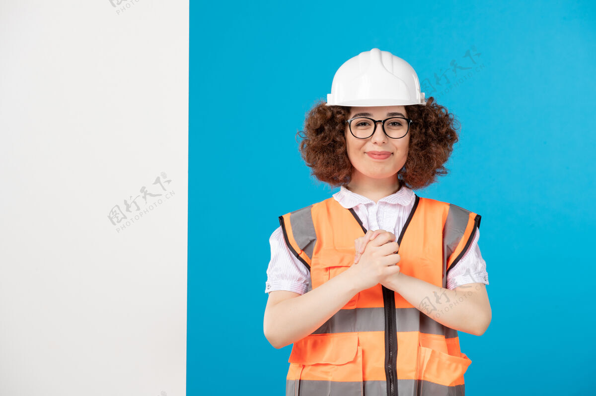 人正面图：身着蓝色制服的微笑女建筑工人工作项目工程师