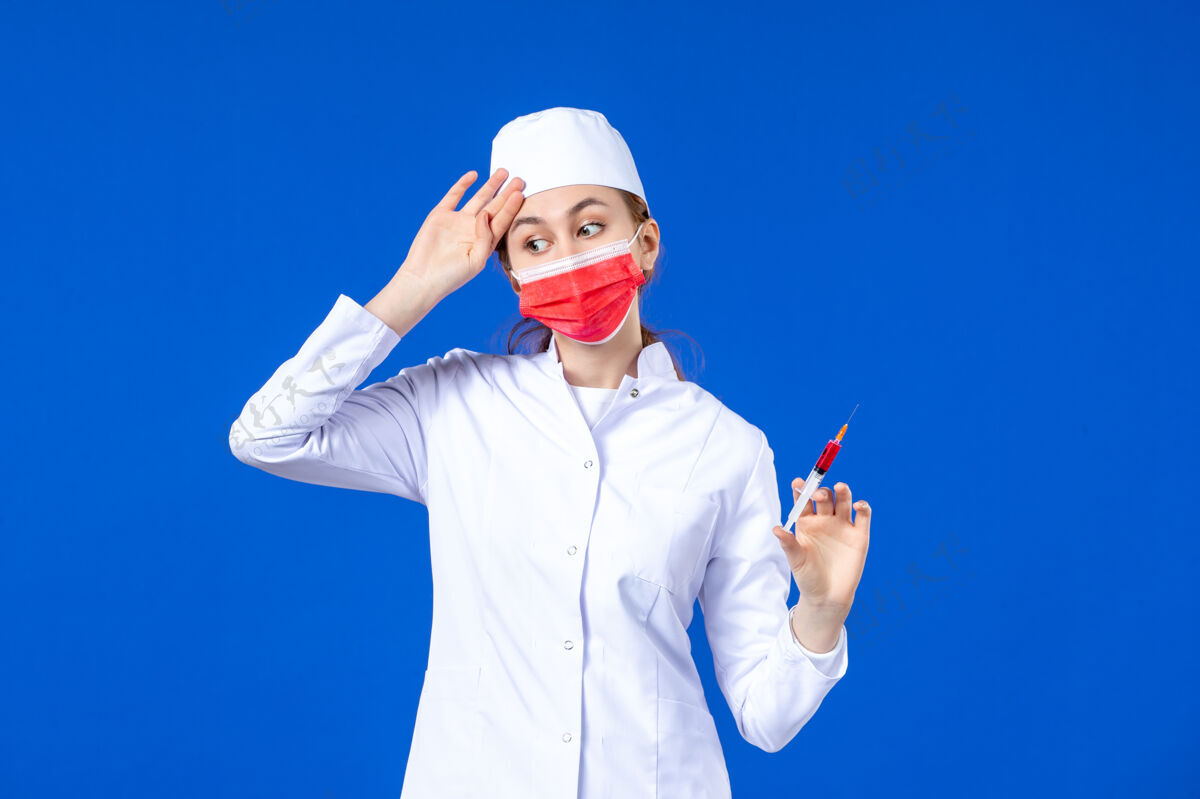 病毒正面图是一位身穿白色医疗服 戴着红色面罩 手上拿着蓝色针剂的女护士注射大流行男性