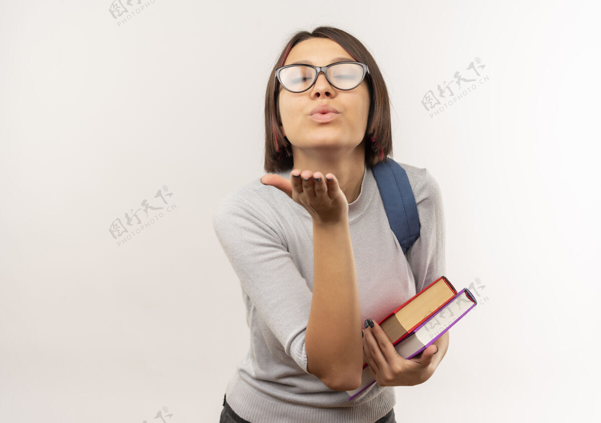 包年轻的女学生戴着眼镜 背着书包 对着镜头吹吻 背景是白色的 还有复印空间吹送吻