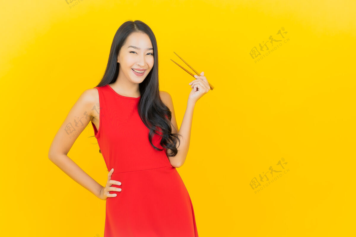 年轻人在黄色的墙上画一幅美丽的亚洲年轻女子拿着筷子准备吃饭饭女孩女人