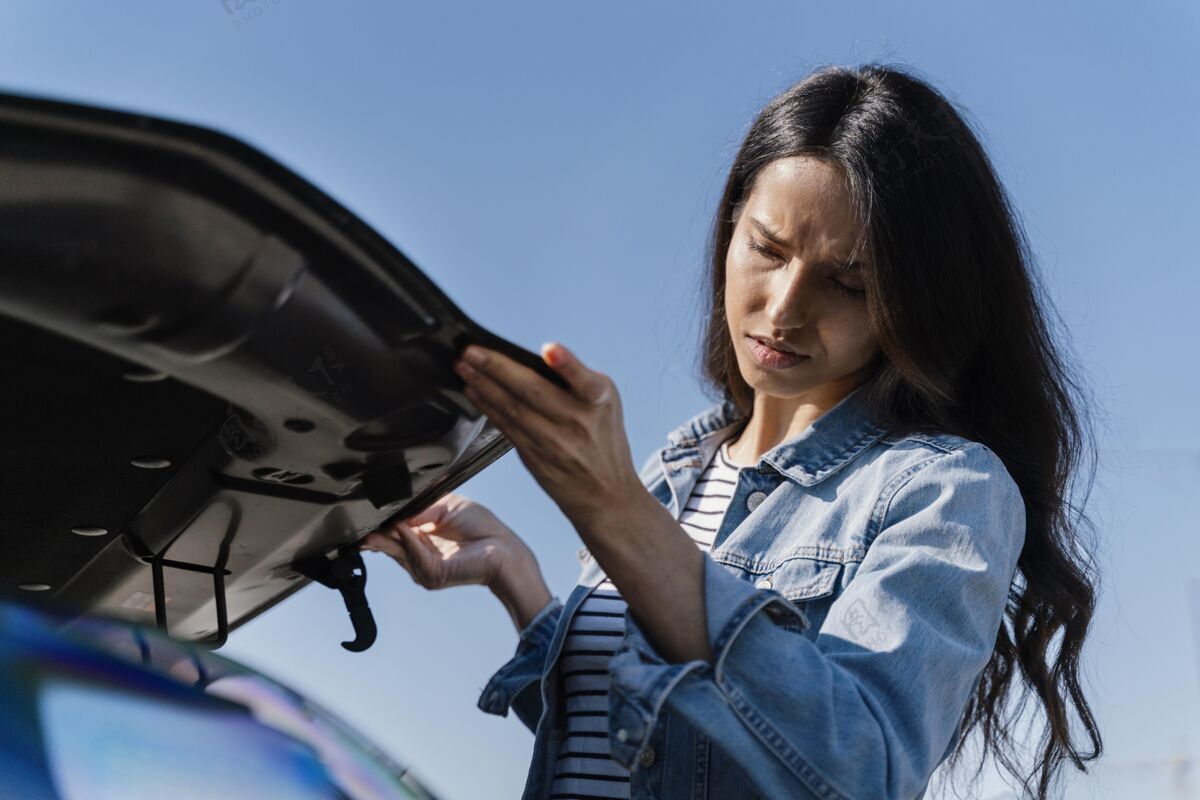 成人女人看着她的车解决问题年轻人司机女人