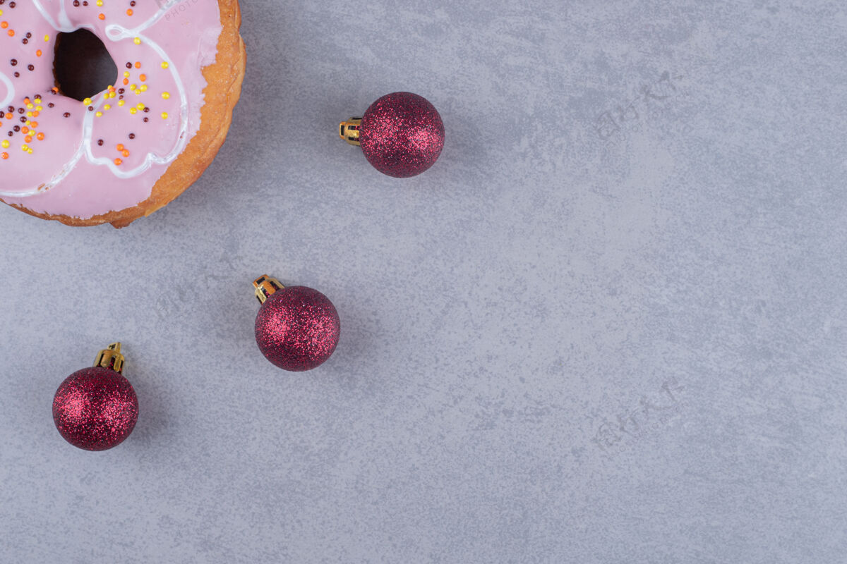 美味三个圣诞饰品和大理石表面的甜甜圈上釉甜点烘焙食品