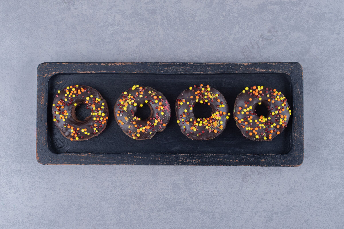 外套在大理石表面的盘子上涂上巧克力的甜甜圈甜点烘焙食品美味