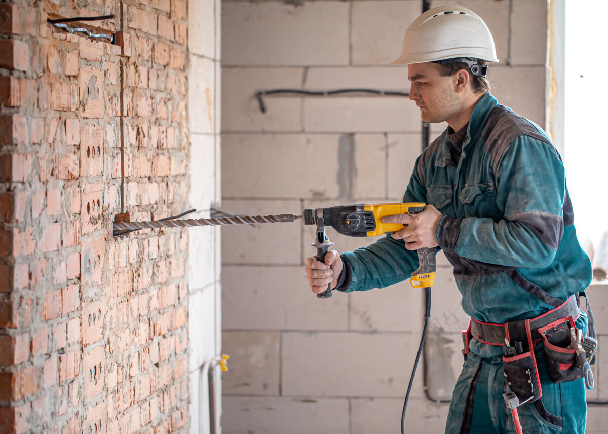 承包商勤杂工在用打孔器钻墙的过程中白专业年轻