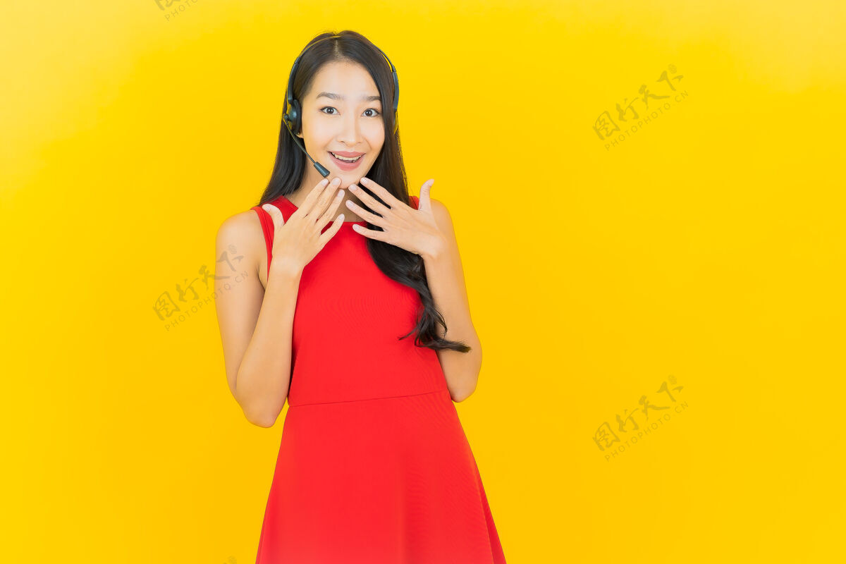 耳机肖像美丽的亚洲年轻女子与耳机沟通和支持呼叫中心服务黄墙耳机商务女性微笑
