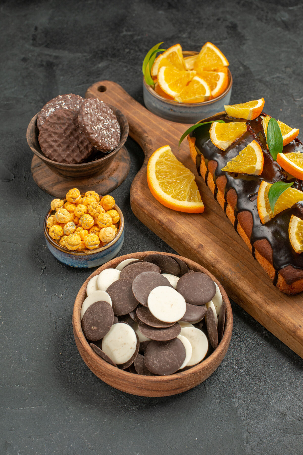 饼干美味蛋糕的侧视图切橘子和饼干放在深色桌子的砧板上水果美食切