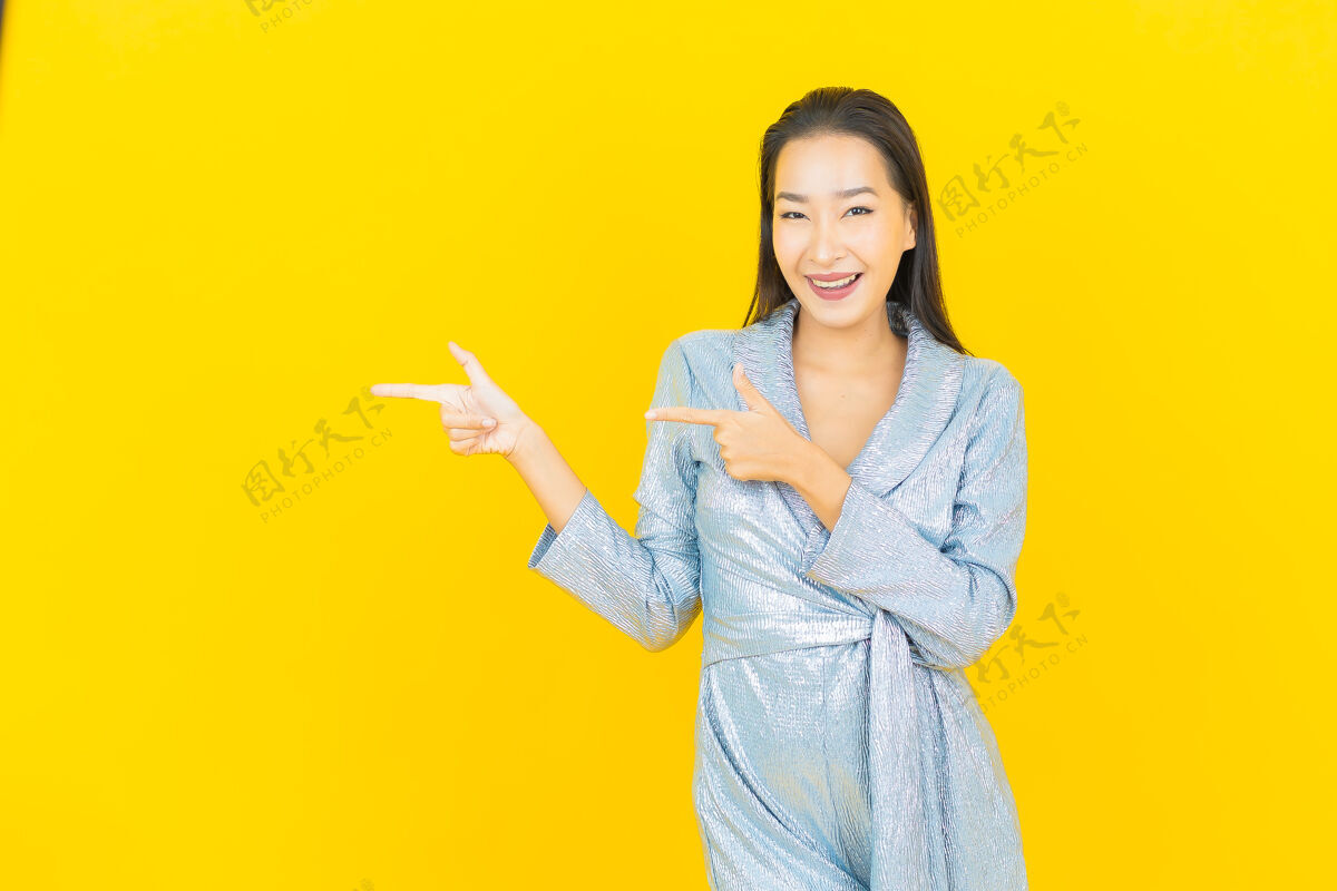 成人在黄色的墙上描绘美丽的亚洲年轻女子微笑着行动时尚明亮中国人