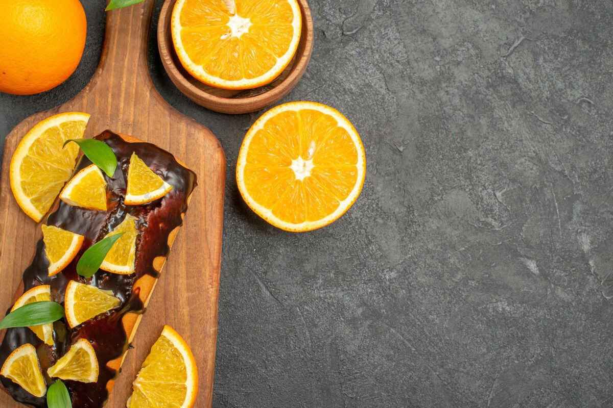 多汁俯瞰图美味的蛋糕整体和削减在切菜板上的黑色桌子上的桔子头顶切的甜橙