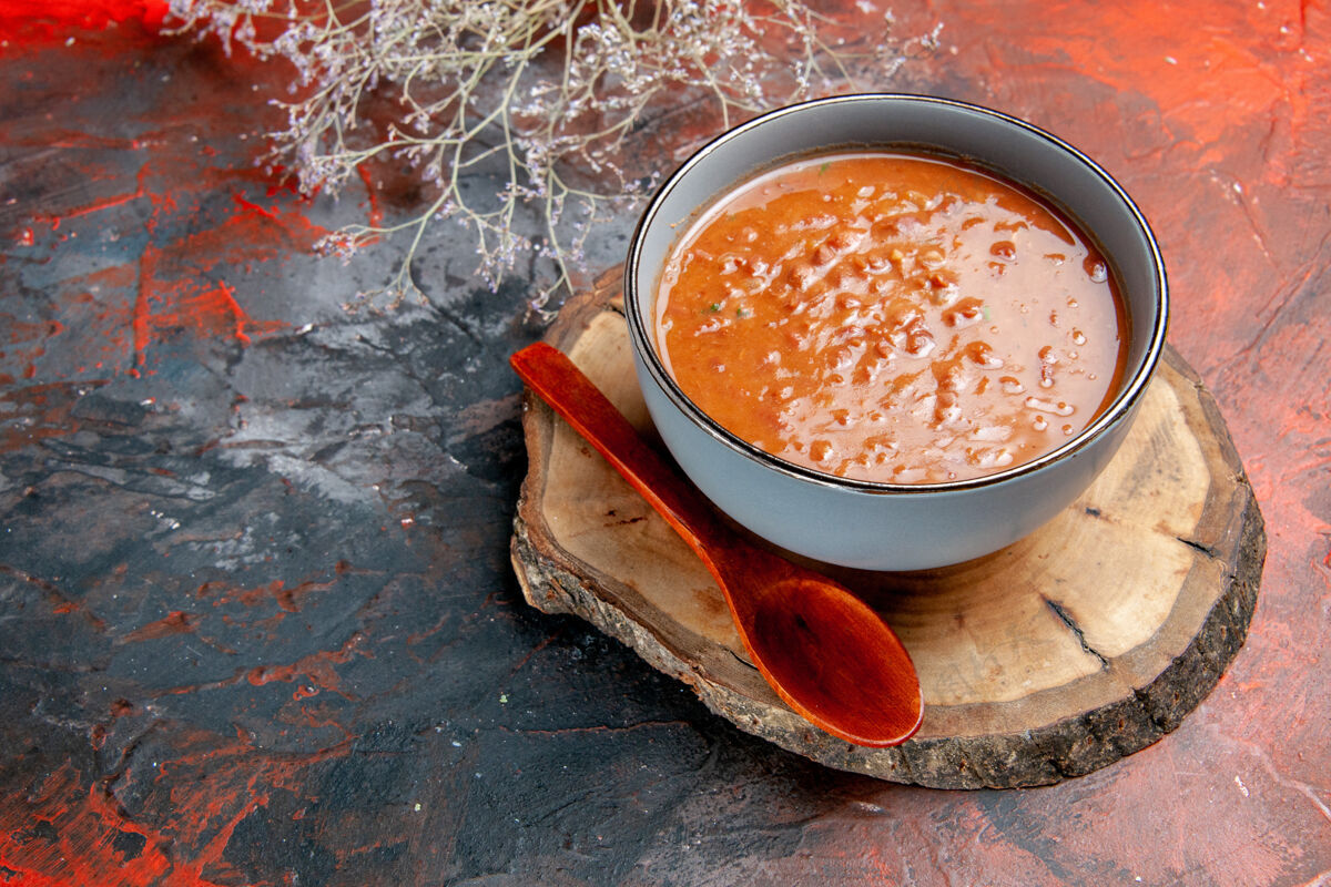 汤特写镜头中的经典番茄汤蓝色碗汤匙木制托盘上的混合颜色的表食物经典热的