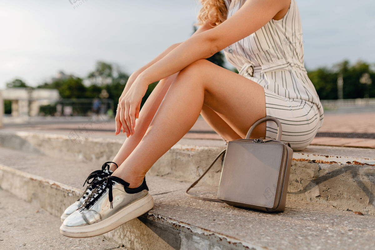 配件时尚女人的配饰走在城市街头 在夏季时尚的风格 腿在运动鞋 灰色钱包手提包微笑女士年轻