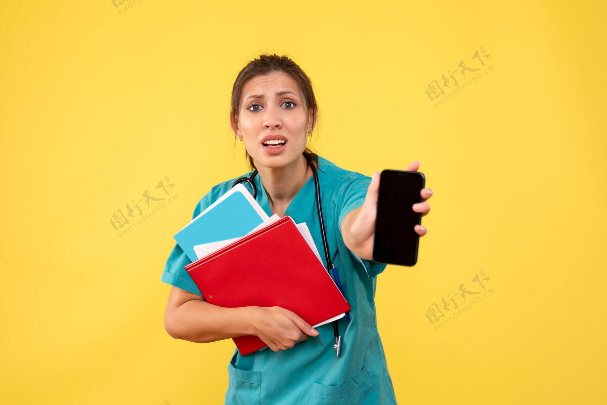 女医生前视图穿着医疗衬衫的女医生拿着黄色背景上的分析和电话电话保持情绪