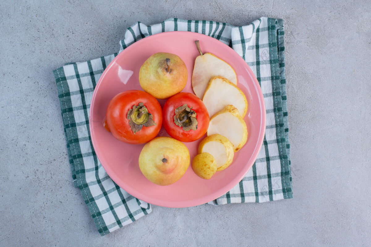 配料一个水果拼盘 在毛巾上放梨和柿子 背景是大理石天然美味新鲜