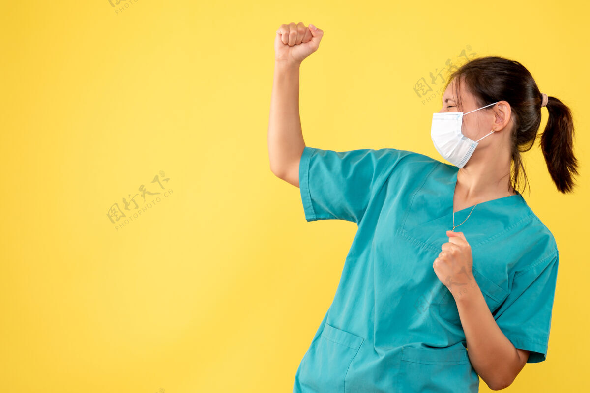正面正面图黄色桌子上穿着医用衬衫和无菌口罩的女医生健康病毒-医学大流行医院病毒黄色运动病毒