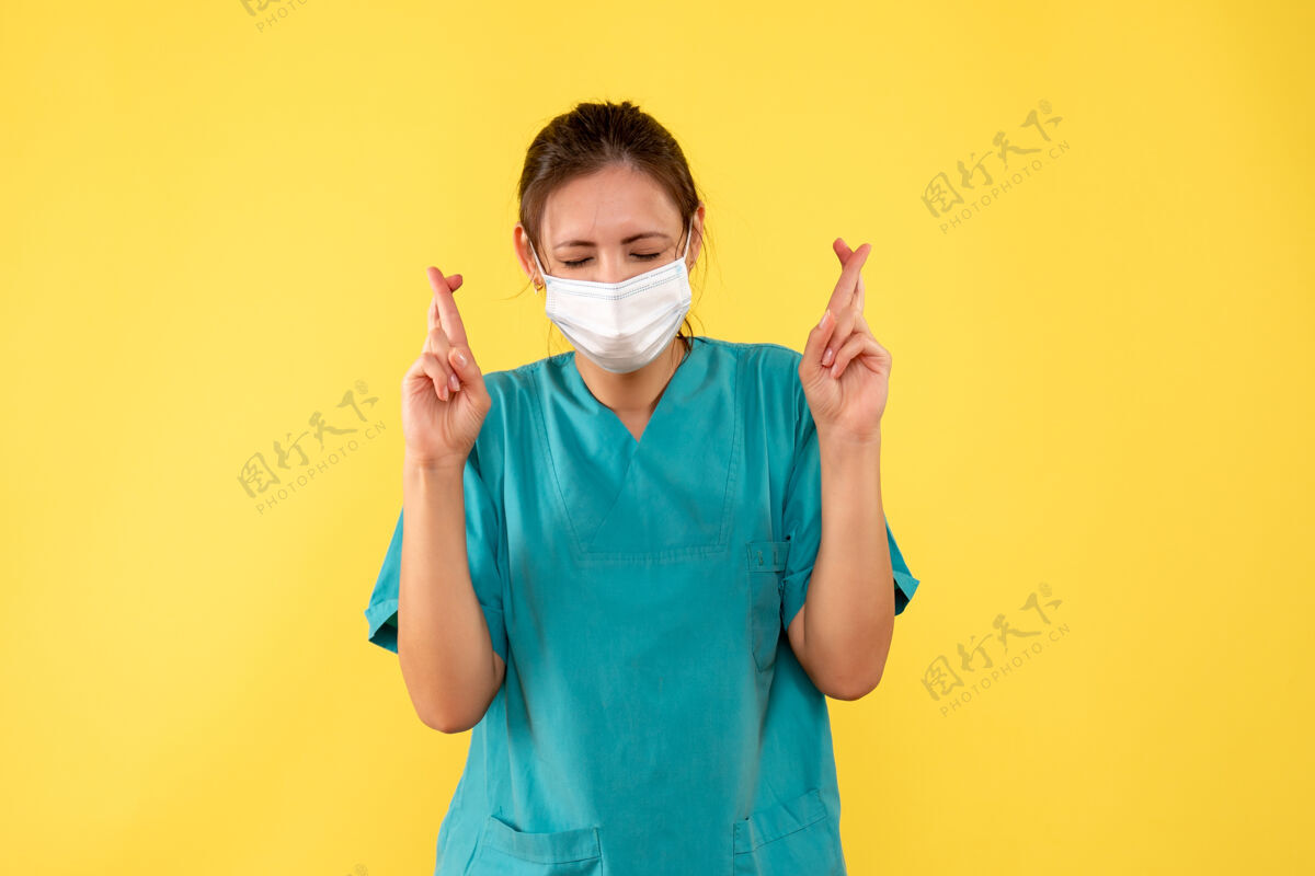 前面正面图黄色桌子上穿着医用衬衫戴着口罩的女医生大流行医院彩色柯维德-健康病毒医生面具衬衫十字架