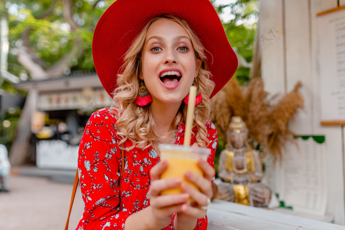 女性迷人时尚的金发微笑女士 头戴草帽 身穿短衫 夏季时尚套装 饮用天然水果鸡尾酒冰沙女孩饮用时尚