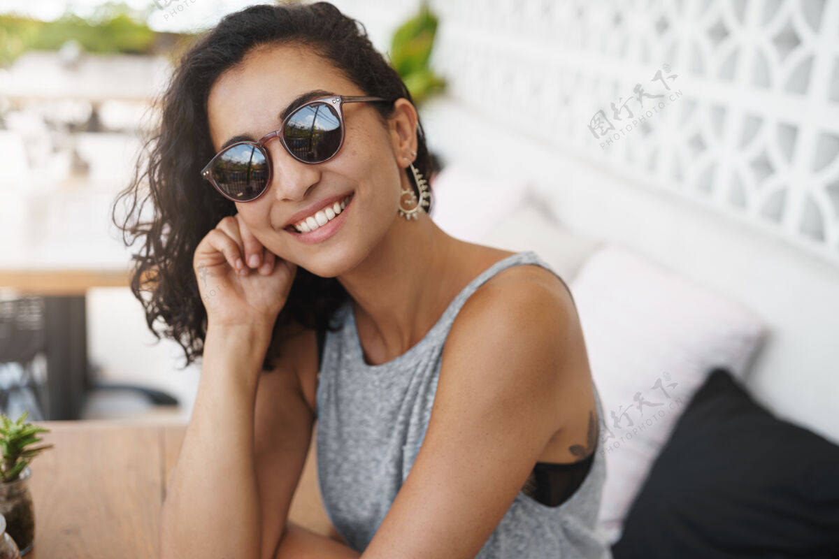 放松戴着墨镜的快乐女人坐在咖啡馆的夏日露台上周末自然日期
