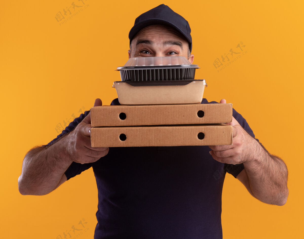 中年人中年送货员穿着制服 戴着帽子 脸上挂着食物容器 披萨盒被隔离在黄色的墙上盒子披萨男人