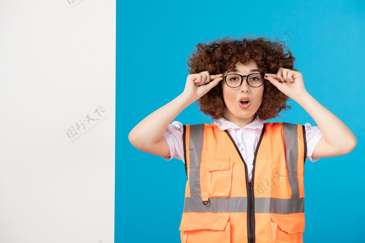 建筑商蓝色墙上穿着制服的女建筑工人的正视图人制服女性