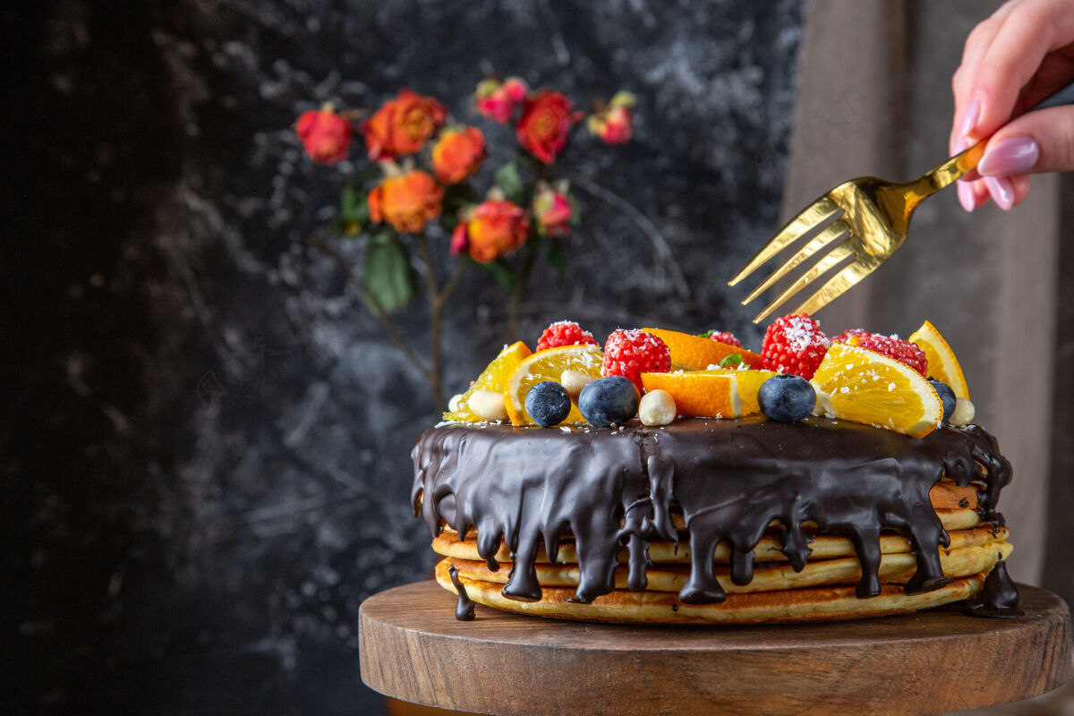风景正面是美味的巧克力蛋糕和新鲜水果在黑暗的墙上零食庆典食物