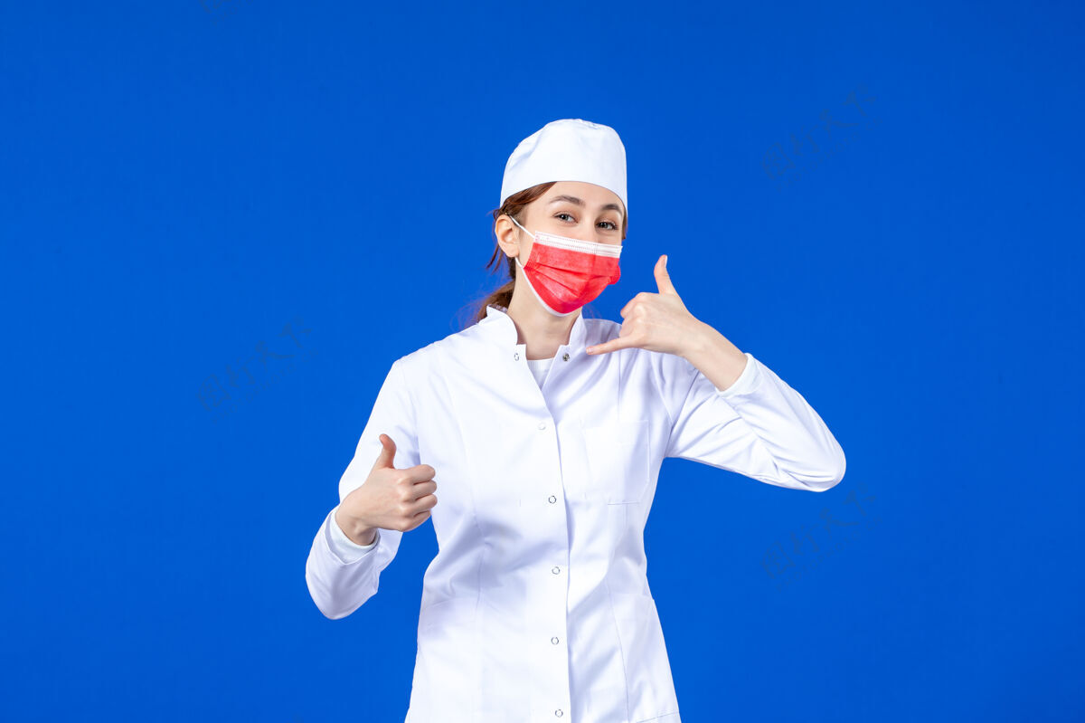 药品正面图身着医疗服的年轻护士 蓝色墙上戴着红色防护面具面罩成人医疗