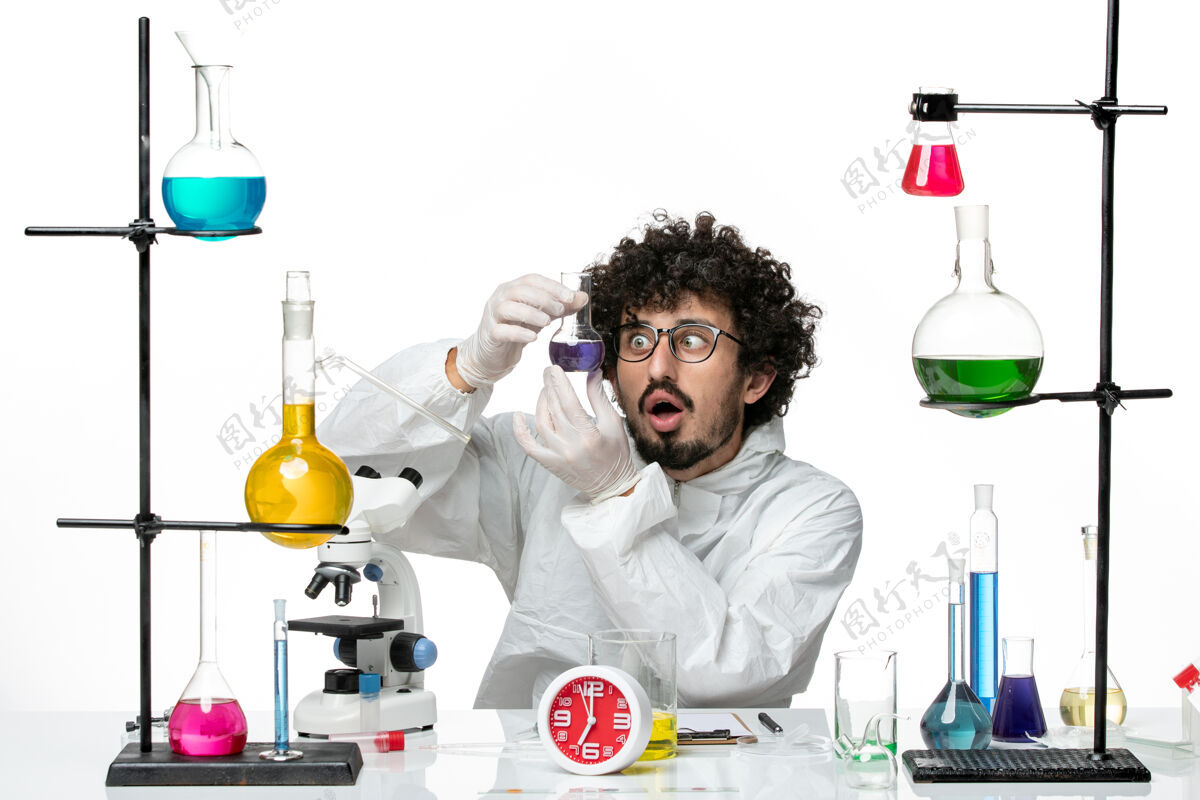化学正面图：年轻的男科学家穿着特制的衣服 拿着白墙上有溶液的烧瓶医学生物学科学
