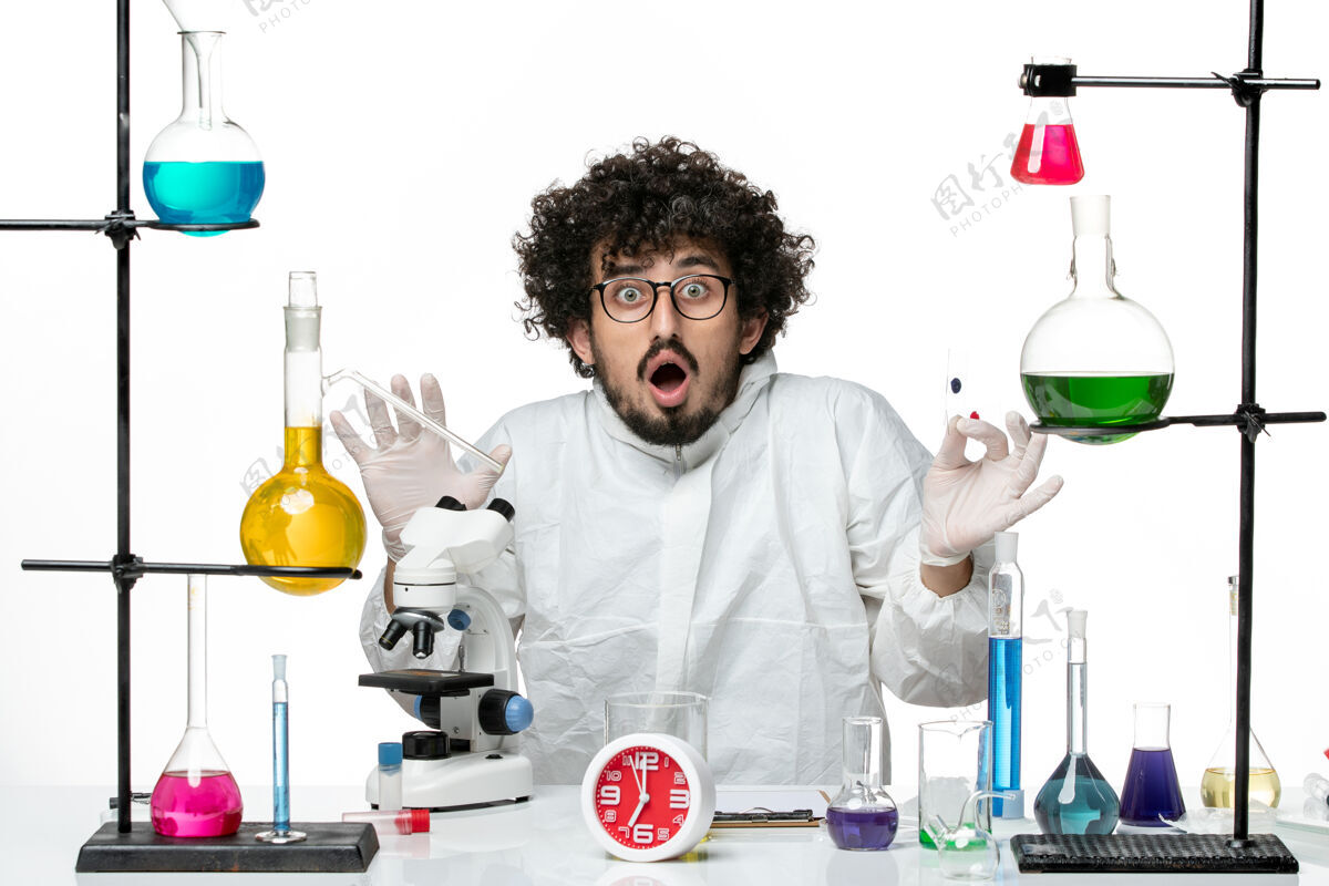光正面图年轻的男科学家穿着特殊的衣服拿着样品 用显微镜在浅白的墙上医生样品实验室