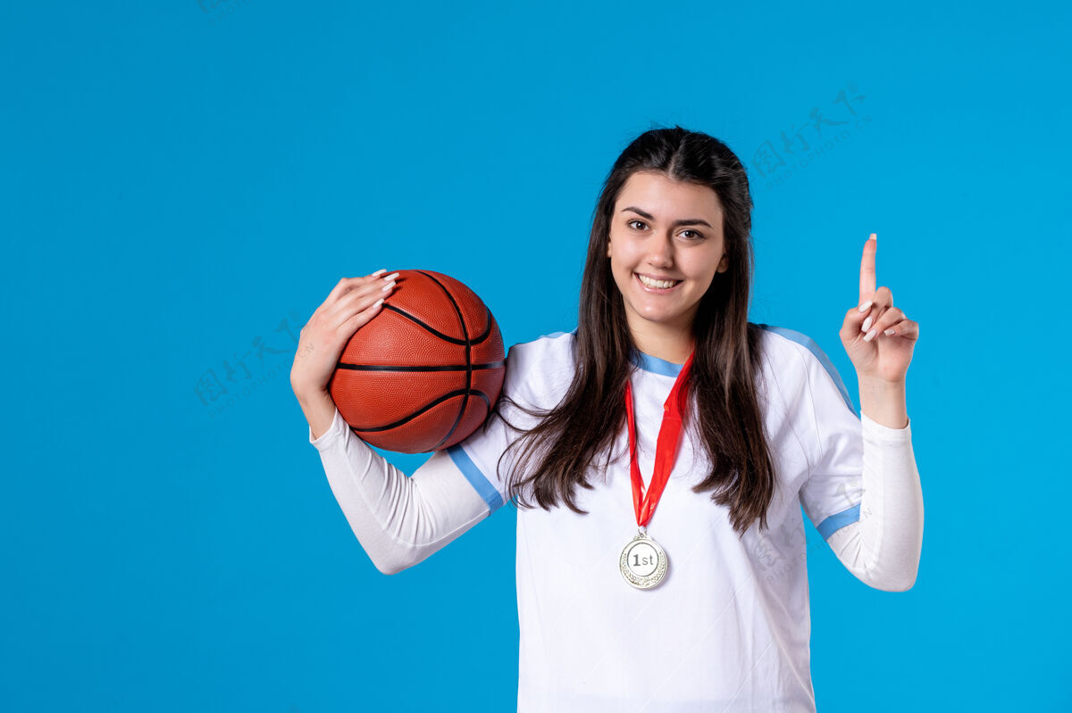 听诊器正面图：年轻女子拿着篮球站在蓝色的墙上蓝色正面年轻女性