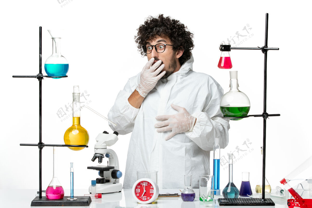 化学正面图身穿白色特殊套装的年轻男性科学家站在桌子旁 拿着解决方案外套视图医学