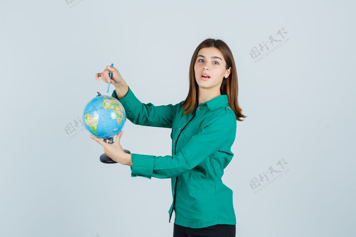 时尚年轻的女士拿着地球仪 穿着衬衫指着地球仪 看上去很困惑前视图女性微笑地球仪