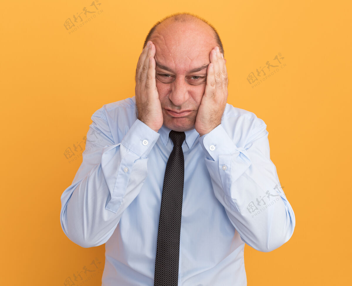 悲伤悲伤的中年男子穿着白色t恤 打着领带 两颊被隔离在橙色的墙上男人穿着中年