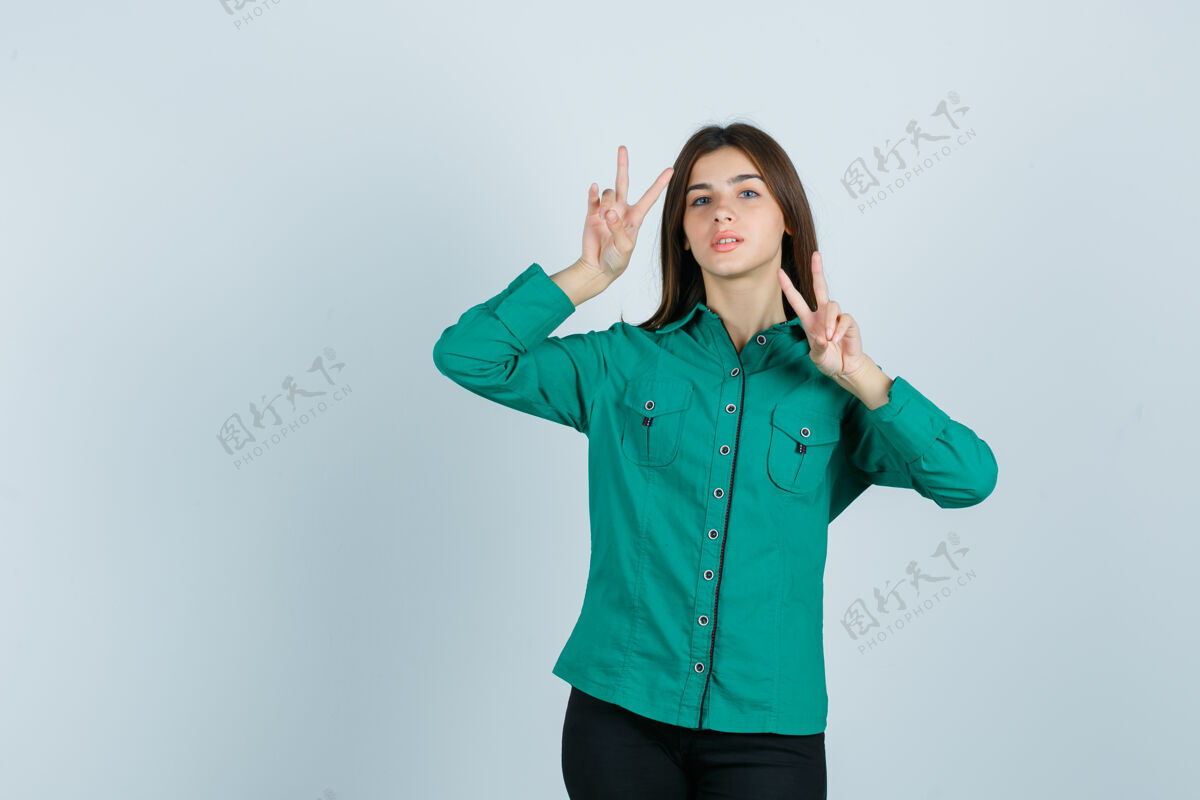 姿势身穿绿色衬衫的年轻女性 展示胜利标志 看起来自信 正面视图女性年轻人表演