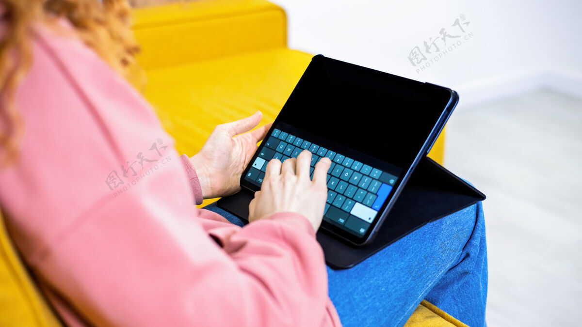 远程小女孩正在沙发上的平板电脑上打字放文字的地方在家工作通讯组虚拟
