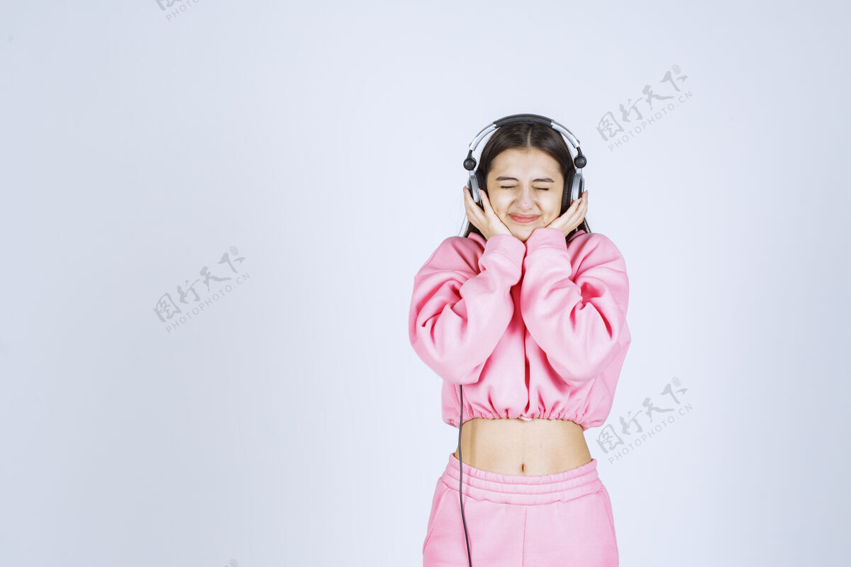 聪明穿着粉色睡衣的女孩 一边听耳机一边玩高质量的照片欢乐推广雇员