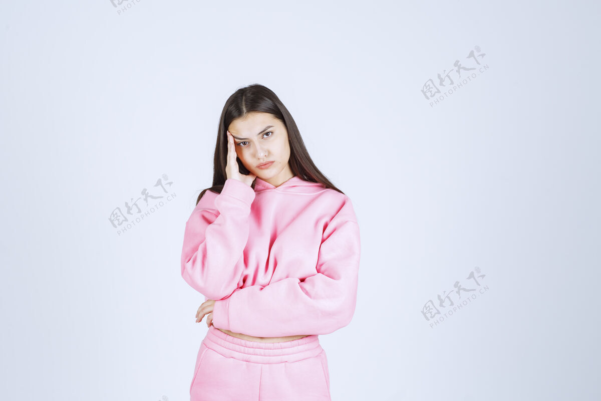 没有经验穿粉红色睡衣的女孩看起来既困惑又体贴人计划姿势