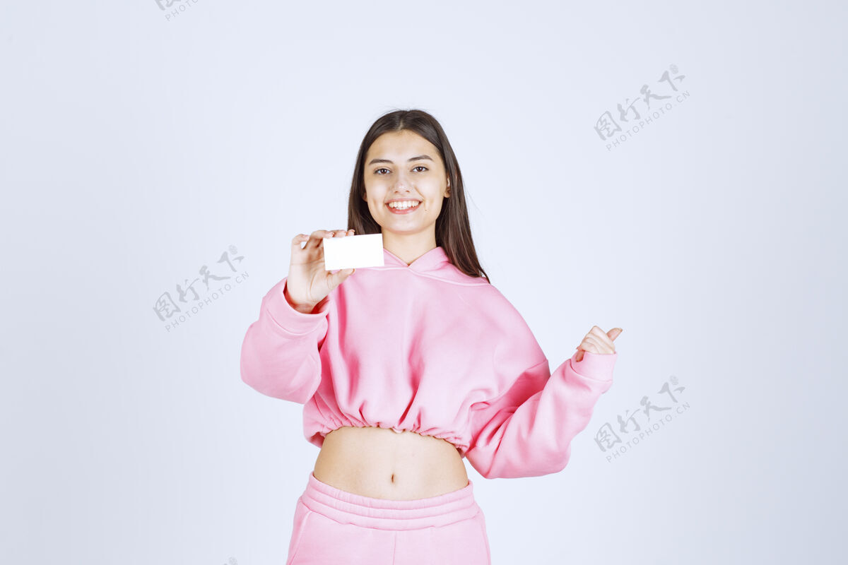 人类穿着粉色睡衣的女孩拿着名片指着别人展示模特介绍
