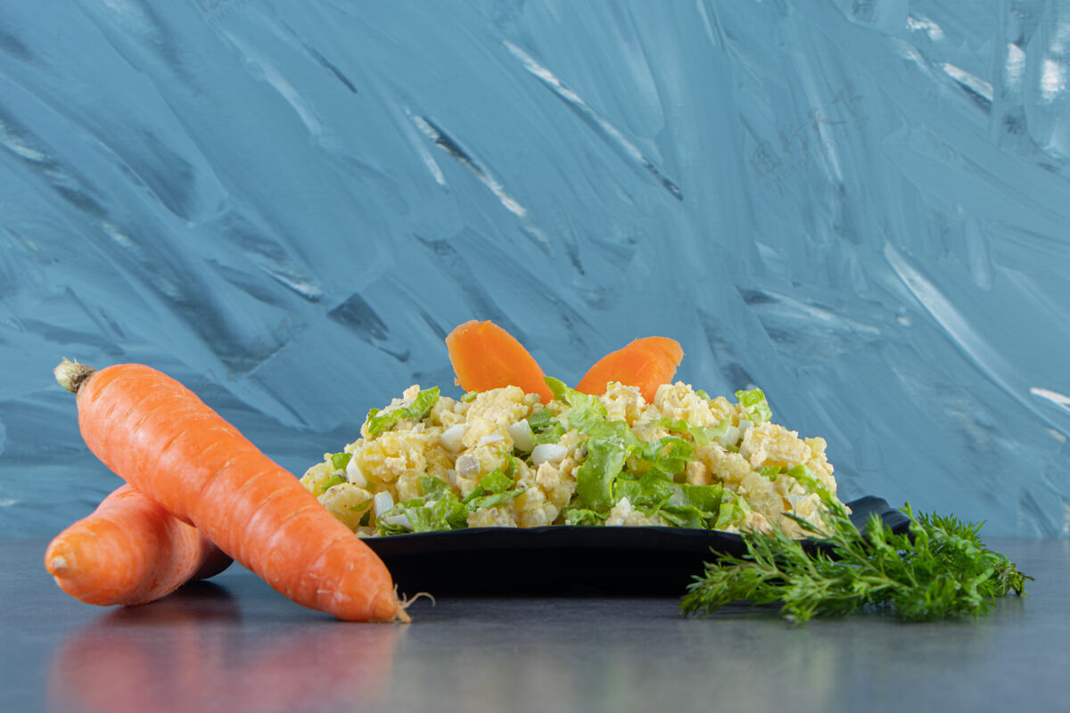 鸡蛋胡萝卜 莳萝和首都沙拉放在盘子里 蓝色背景一餐胡萝卜土豆