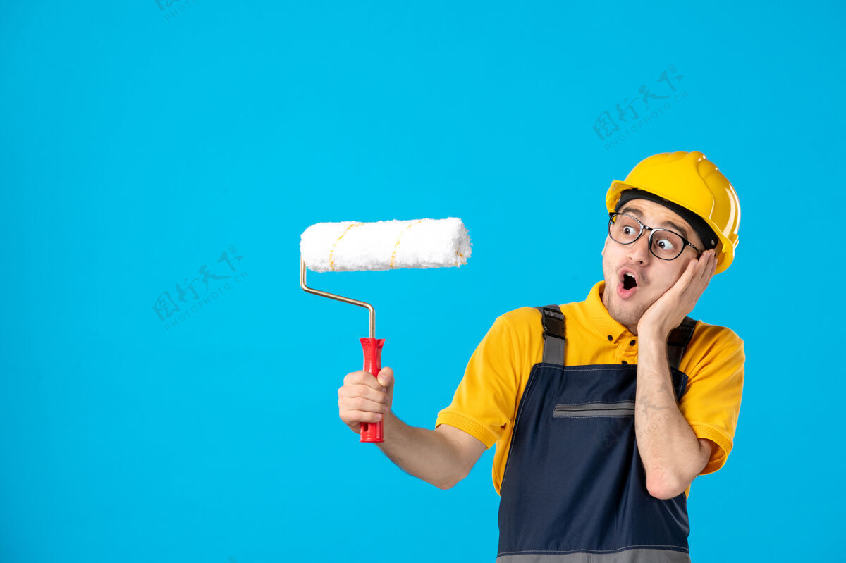 冷冻甜点身穿黄色制服 蓝色油漆辊的震惊男工人的正视图制服建筑冰棍