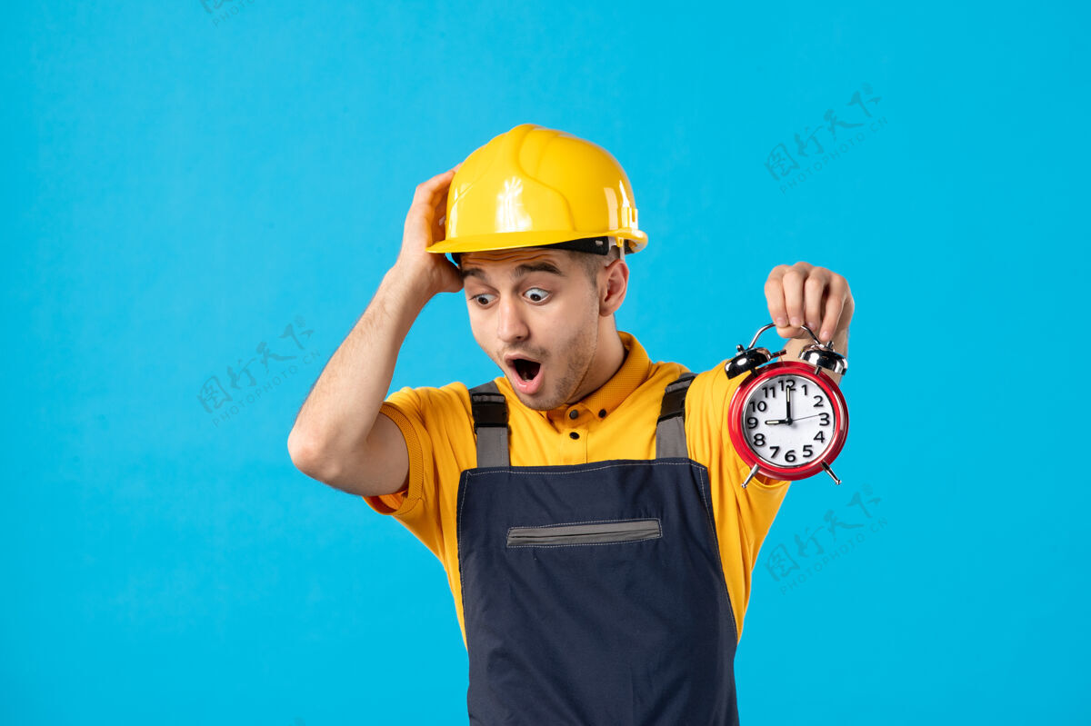 承包商穿着制服的男工人的正视图 蓝色的时钟已经迟到了头盔建筑工人施工