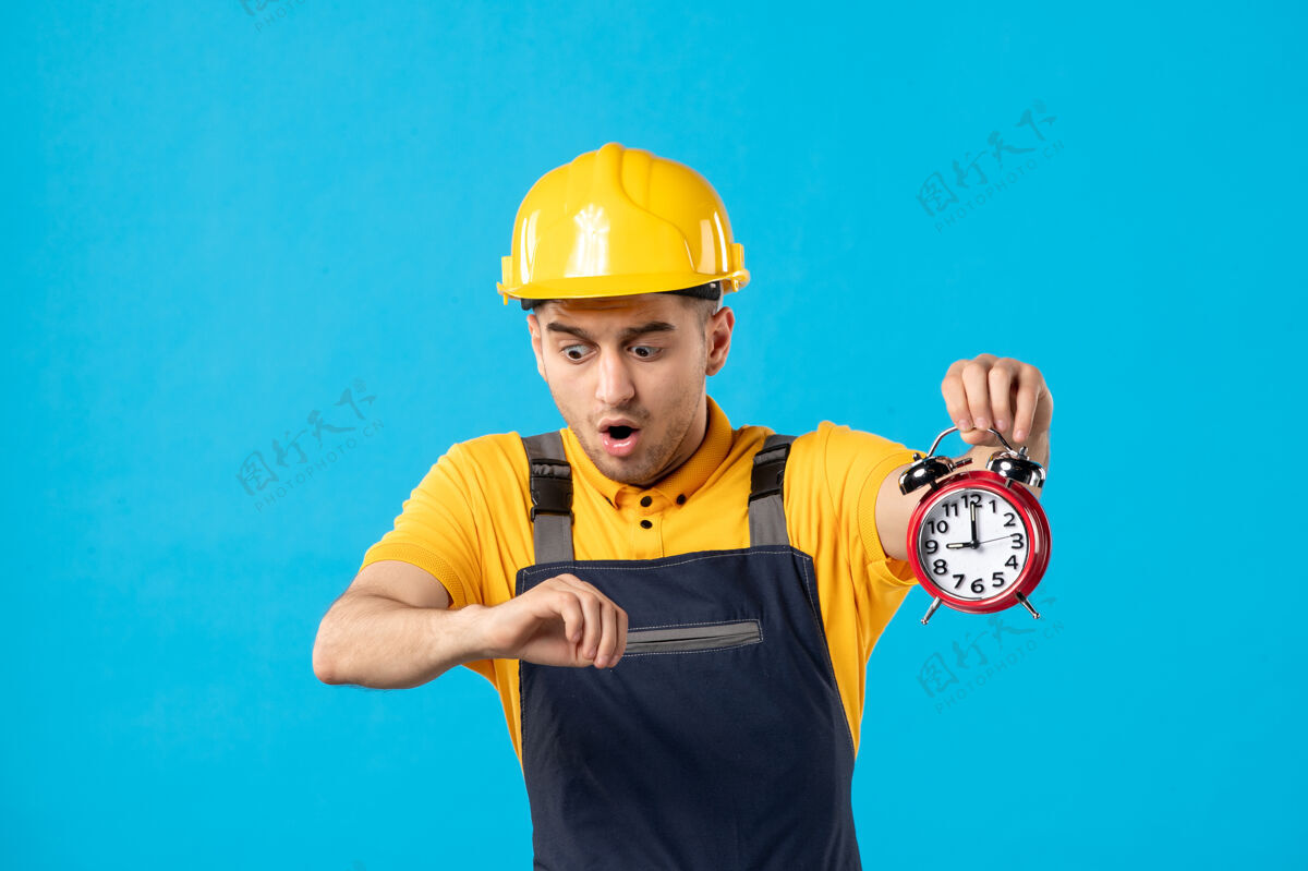 建筑商穿着制服的男工人的正视图 蓝色的时钟很晚承包商时钟头盔