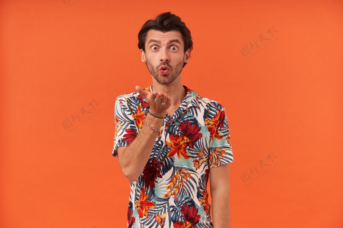深色头发一个快乐迷人的年轻人 穿着五颜六色的衬衫 站着向镜头送去一个吻夏威夷人镜头可爱