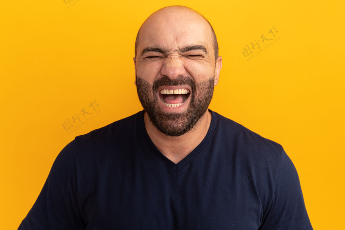 兴奋一个穿着海军t恤的大胡子男人站在橘色的墙上兴奋地尖叫着尖叫站起来伙计