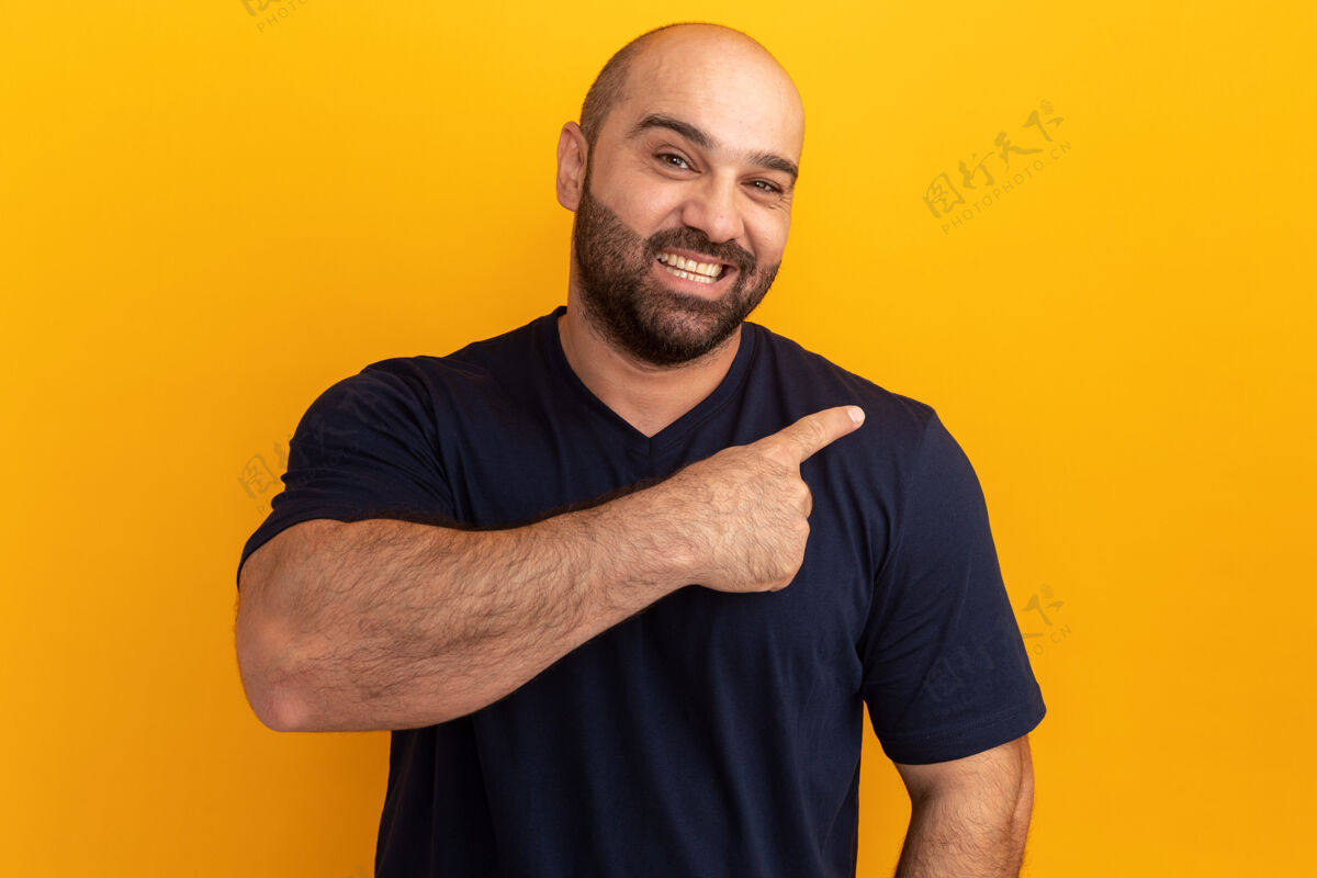 目录一个留着胡子的男人 穿着海军蓝t恤 脸上带着微笑 用食指指着站在橙色墙上的一边男人侧线手指