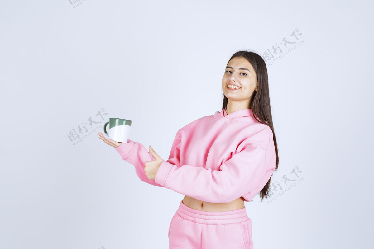 热穿着粉色睡衣的女孩拿着一个咖啡杯 感觉很开心年轻微笑人类