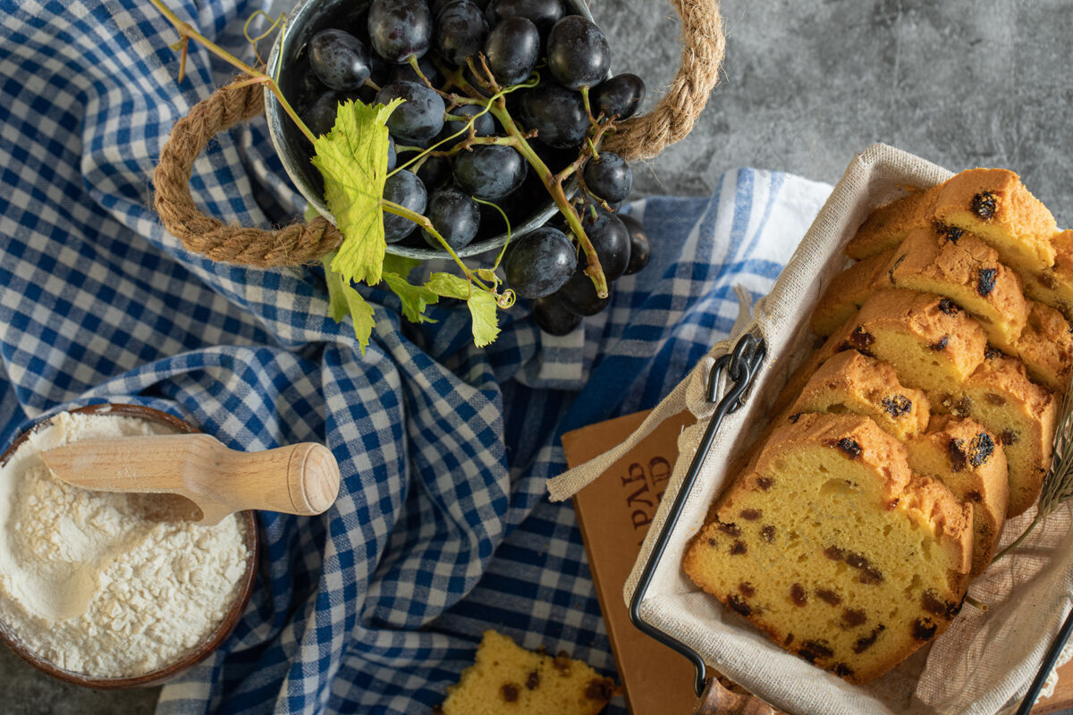 桌布葡萄干蛋糕 一碗面粉和葡萄放在大理石表面篮子饼干葡萄干